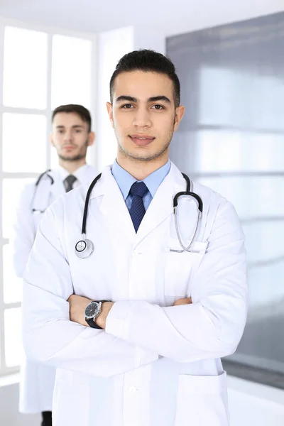 Arabischer Arzt, der mit einem kaukasischen Kollegen in einer Arztpraxis oder Klinik steht. Vielfältiges Ärzteteam, Medizin und Gesundheitskonzept — Stockfoto