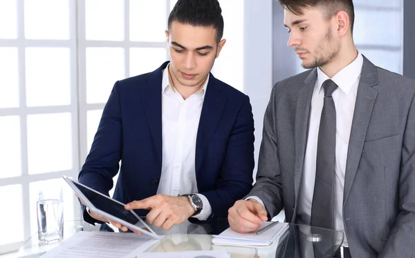 Twee zakenmensen of partners werken met een tablet computer aan het bureau in het moderne kantoor. Headshot van arabische mannelijke ondernemer of manager met collega op het werk. Multietnisch teamwerk, partnerschap en — Stockfoto