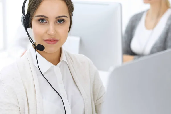 Centro de llamadas. Grupo de operadores en el trabajo. Enfócate en la hermosa recepcionista en auriculares en la oficina de servicio al cliente de color blanco. Concepto empresarial —  Fotos de Stock