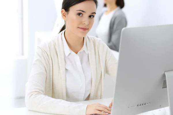 사무실에서 컴퓨터로 일하는 비지니스 여성, 배경에 있는 여성 동료. 책상에 앉아 있는 동안 변호사나 회계사의 헤드 샷 — 스톡 사진