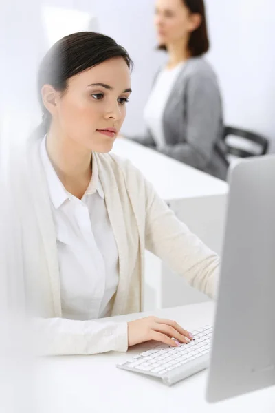 Geschäftsfrau im Büro mit Computer, Kollegin im Hintergrund. Kopfschuss des Rechtsanwalts oder Buchhalters bei der Arbeit, während er am Schreibtisch sitzt — Stockfoto