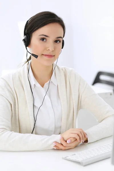 Centro de llamadas. Hermosa recepcionista mujer sentada en auriculares en la oficina de servicio al cliente. Grupo de operadores en el trabajo. Concepto empresarial —  Fotos de Stock