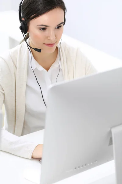 Centro de llamadas. Hermosa recepcionista mujer sentada en auriculares en la oficina de servicio al cliente. Grupo de operadores en el trabajo. Concepto empresarial —  Fotos de Stock