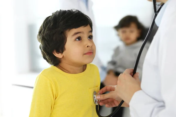 Médico examinando uma criança paciente por estetoscópio. Rapaz árabe bonito na consulta médica. Conceito de medicina e saúde — Fotografia de Stock