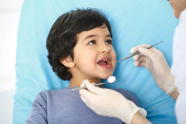 Kleiner arabischer Junge sitzt mit offenem Mund am Zahnarztstuhl während der mündlichen Untersuchung während des Arztes. Zahnarztbesuche. Medizin und Stomatologie-Konzept — Stockfoto