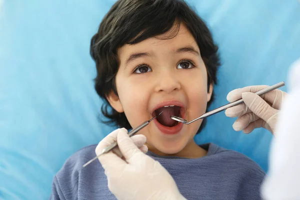 Mały arabski chłopiec siedzący na krześle dentystycznym z otwartymi ustami podczas kontroli doustnej, podczas gdy lekarz. Odwiedzam gabinet dentystyczny. Koncepcja medycyny i stomatologii — Zdjęcie stockowe