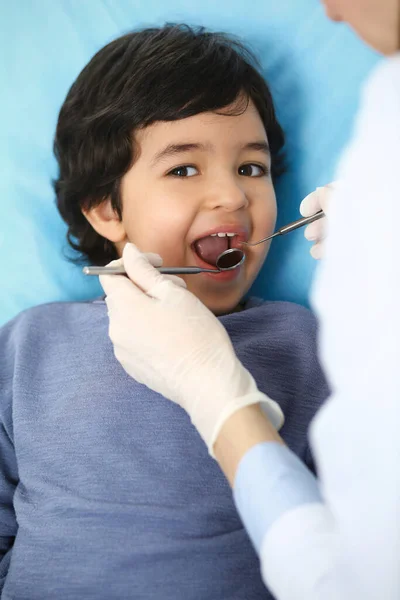 Menino árabe sentado na cadeira dentária com a boca aberta durante o check-up oral, enquanto médico. Consulta ao dentista. Conceito de medicina e estomatologia — Fotografia de Stock