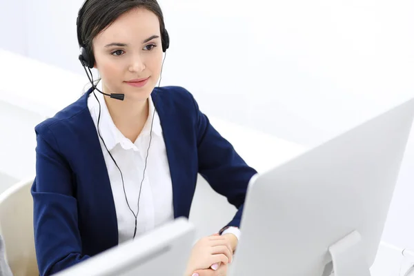 Call center. Beautiful woman receptionist sitting in headset at customer service office. Group of operators at work. Business concept Stock Image