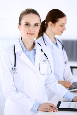 Hastanede çalışan bir grup doktor. Doktor resepsiyonda beklerken tıbbi belge ya da reçete dolduruyor. Tıp ve sağlık hizmetleri kavramındaki veriler