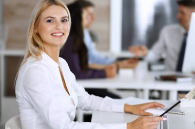 Modern ofisteki işyerinde bilgisayar kullanan bir iş kadını. Sekreter ya da kadın avukat gülümsüyor ve mutlu görünüyor. Zevk ve başarı için çalışmak