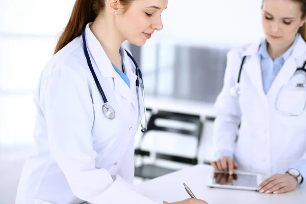 Group of doctors at work in hospital. Physician filling up medical documents or prescription while standing at reception desk. Data in medicine and health care concept — Stock Photo, Image