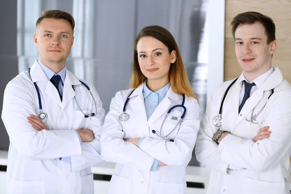 Grupo de médicos modernos de pie como un equipo con los brazos cruzados en la oficina del hospital. Médicos listos para examinar y ayudar a los pacientes. Ayuda médica, seguro de salud, mejor tratamiento y medicina — Foto de Stock