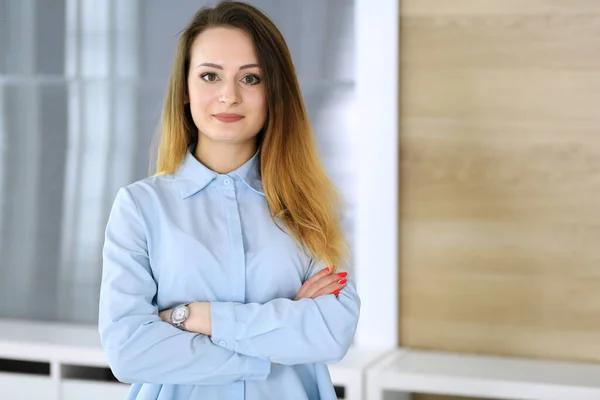 Modern ofisteki iş yerinde iş kadını vesikalığı. Kollarını kavuşturup dik duran kimliği belirsiz bir iş kadını. Genç muhasebeci ya da sekreter iyi görünüyor.