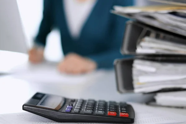 Hesap makinesi ve kağıtlar iş kadını ya da ofisteki büroda çalışan muhasebeci tarafından incelenmeyi bekliyor. İç Denetim ve vergi kavramı