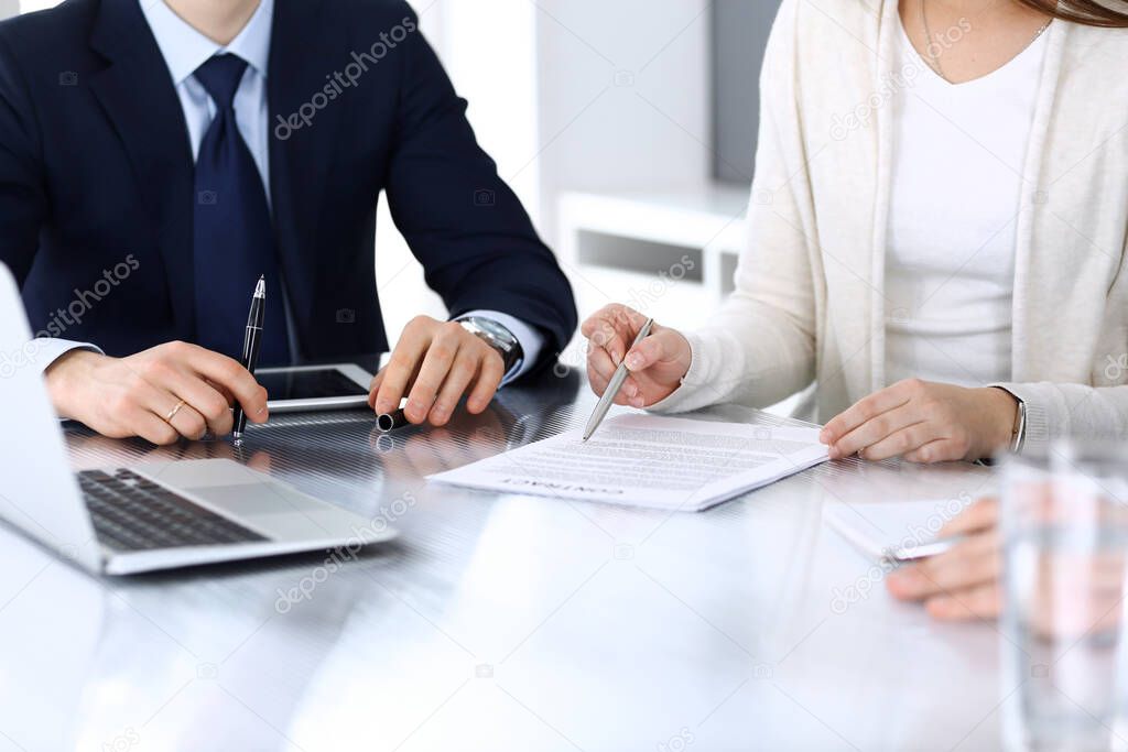 Business people discussing contract working together at meeting at the glass desk in modern office. Unknown businessman and woman with colleagues or lawyers at negotiation. Teamwork and partnership