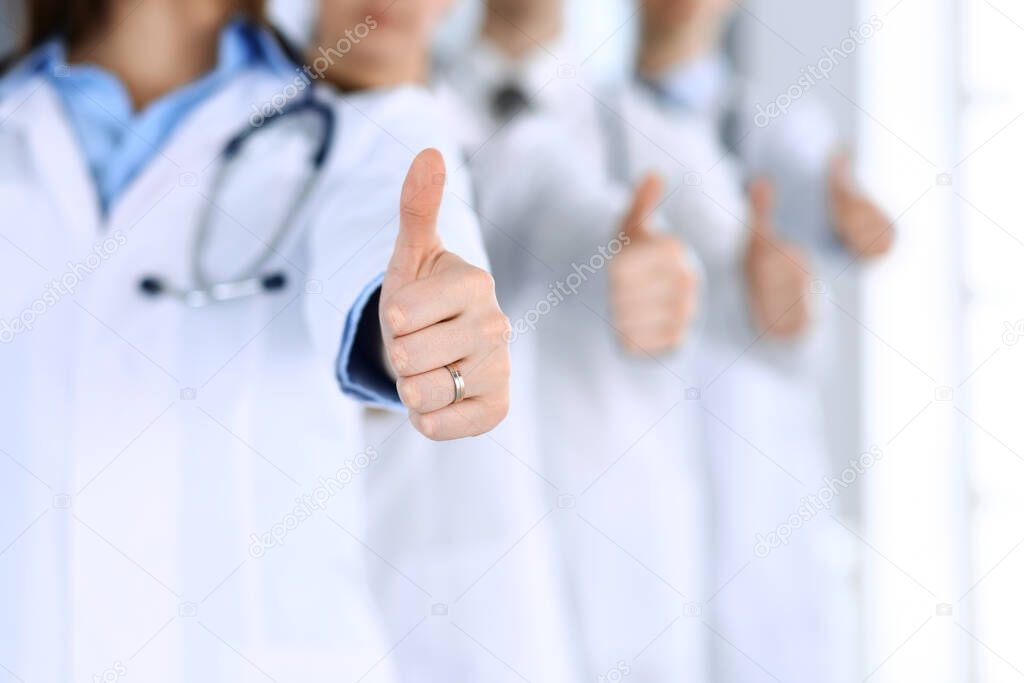 Group of modern doctors standing as a team with thumbs up in hospital office. Physicians ready to examine and help patients. Medical help, insurance in health care, best desease treatment and medicine