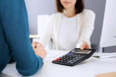 Mali durumu kontrol eden ya da vergi formları için hesap makinesinin geliri ile sayan, elleri yakın çekim. İş kadını ofisteki masada iş arkadaşıyla oturuyor ve çalışıyor. Vergi ve Denetim kavramı