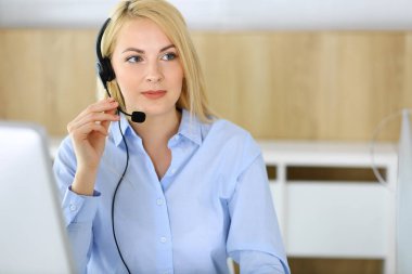 Merkezi ara. Müşteri hizmetleri ofisinde kulaklık takan sarışın bir iş kadını. Telesellerin iş ya da ev işgali kavramı