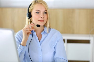 Merkezi ara. Müşteri hizmetleri ofisinde kulaklık takan sarışın bir iş kadını. Telesellerin iş ya da ev işgali kavramı