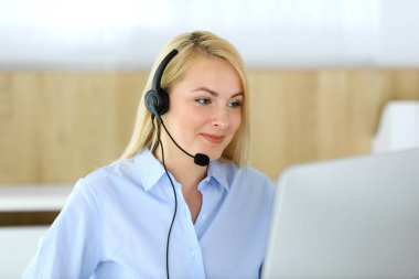 Merkezi ara. Müşteri hizmetleri ofisinde kulaklık takan sarışın bir iş kadını. Telesellerin iş ya da ev işgali kavramı