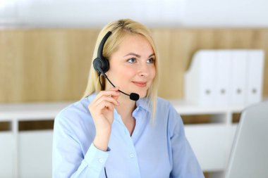Merkezi ara. Müşteri hizmetleri ofisinde kulaklık takan sarışın bir iş kadını. Telesellerin iş ya da ev işgali kavramı