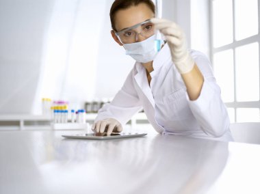 Kadın laboratuvar asistanı hastanede kan örneğini inceliyor. İlaç, sağlık ve koronavirüs koruma kavramı