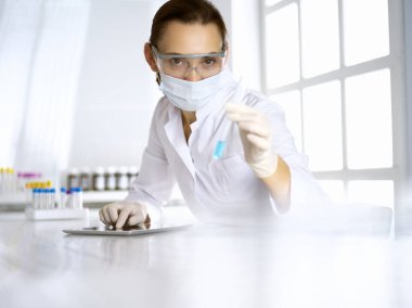 Kadın laboratuvar asistanı hastanede kan örneğini inceliyor. İlaç, sağlık ve koronavirüs koruma kavramı