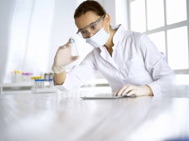 Kadın laboratuvar asistanı hastanede kan örneğini inceliyor. İlaç, sağlık ve koronavirüs koruma kavramı