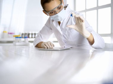 Kadın laboratuvar asistanı hastanede kan örneğini inceliyor. İlaç, sağlık ve koronavirüs koruma kavramı