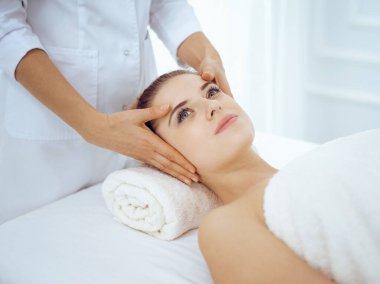 Genç ve sarışın kadın spa salonunda yüz masajından zevk alıyor. Güzellik konsepti