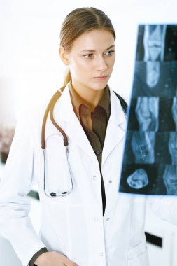 Kadın doktor hastanede röntgen filmini inceliyor. Güneşli klinikte çalışan bir cerrah ya da ortopedist. Tıp ve sağlık hizmetleri kavramı