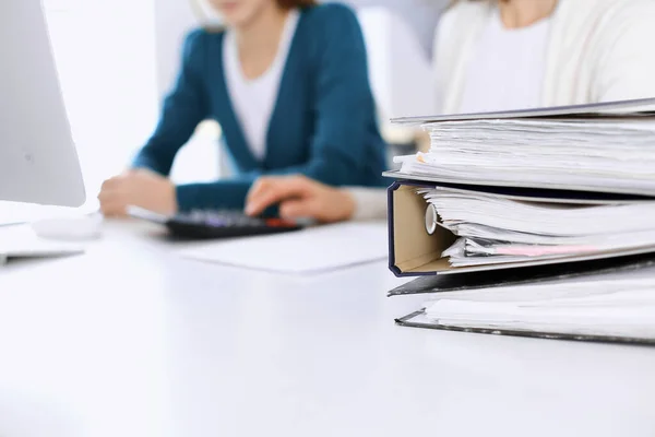 Binders with papers are waiting to be processed by business woman or bookkeeper working at the desk in office back in blur. Audit and tax concept — Stock Photo, Image