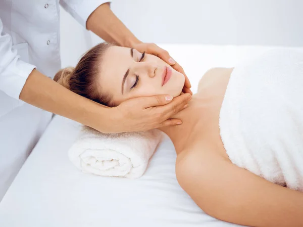 Jonge en blonde vrouw geniet van gezichtsmassage in spa salon. Schoonheidsconcept — Stockfoto