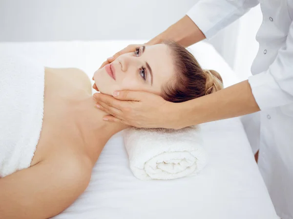 Jonge en blonde vrouw geniet van gezichtsmassage in spa salon. Schoonheidsconcept — Stockfoto