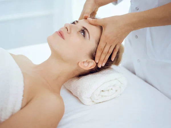 Jonge en blonde vrouw geniet van gezichtsmassage in spa salon. Schoonheidsconcept — Stockfoto