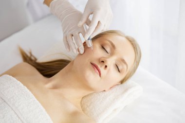 Güzellik doktoru, beyaz kadın yüzüne şırıngayla güzellik prosedürü uyguluyor. Kozmetik tıp ve cerrahi, güzellik enjeksiyonları konsepti