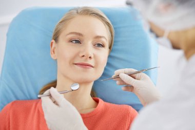 Gülümseyen beyaz kadın dişçi kliniğinde dişçi tarafından muayene ediliyor. Sağlıklı dişler ve ilaçlar, stomatoloji konsepti