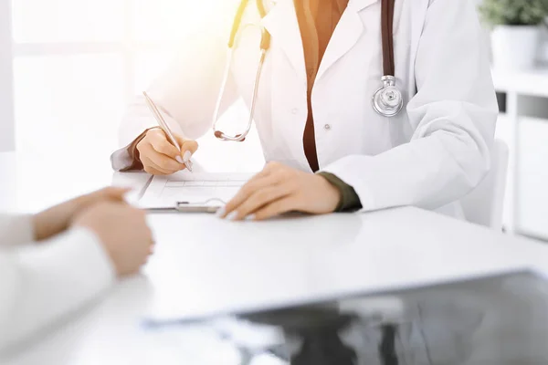 Güneşli klinikteki tıbbi muayenede oturan ve konuşan kimliği belirsiz kadın-doktor ve kadın hasta, yakın plan. İlaç geçmişini dolduran bir terapist. Tıp konsepti