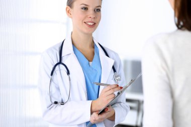 Muayene sırasında doktor ve hasta. Acil serviste dikilirken ilaç geçmişini dolduran bir doktor, portre çekimi. İlaç ve sağlık hizmetleri kavramı