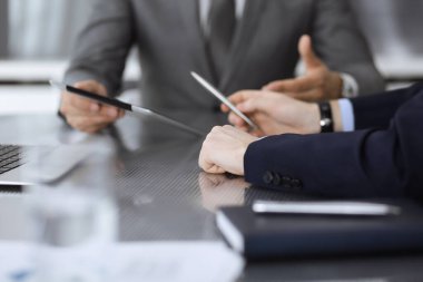 Bilinmeyen işadamı, modern ofisteki cam masada otururken tablet bilgisayar kullanıyor ve iş arkadaşıyla birlikte çalışıyor. Takım çalışması ve ortaklık kavramı