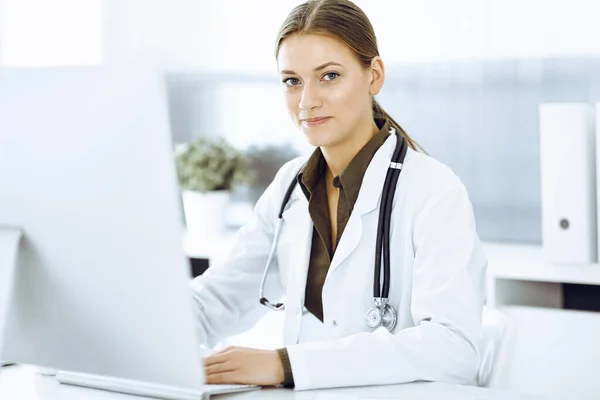病院の机に座っている間にパソコンに入力した女性医師。医療や医療のデータ — ストック写真