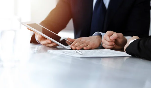 Gente de negocios que usa tableta mientras trabajan juntos en la soleada oficina moderna. Hombre de negocios desconocido con colega en el lugar de trabajo. Trabajo en equipo y concepto de asociación — Foto de Stock