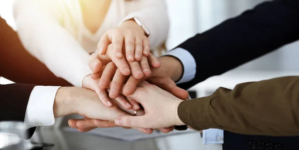 チームワークを示し、手をつなぎ、または日当たりの良いオフィスで5を与えるビジネスの人々グループ。無名のビジネスマンや女性が手で輪になって — ストック写真