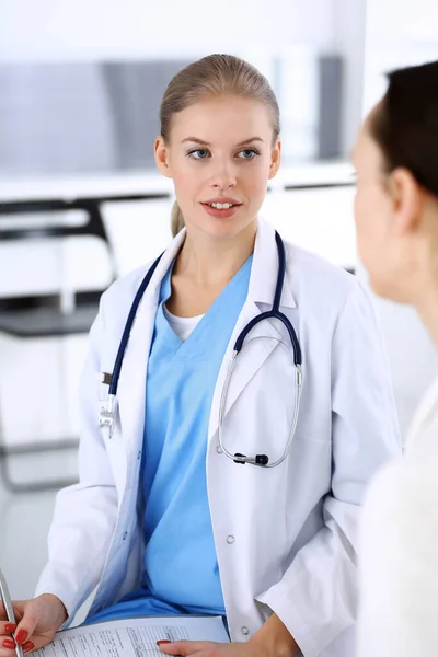 Doctor y paciente durante la consulta. Médico en el trabajo llenando el historial de medicamentos mientras está sentado en el hospital de emergencia, sesión de fotos. Concepto de medicina y salud — Foto de Stock