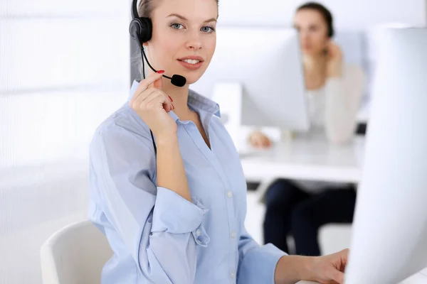 Call center office. Beautiful blonde woman using computer and headset for consulting clients online. Group of operators working as customer service occupation. Business people concept Royalty Free Stock Images