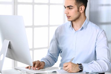 Modern ofiste bilgisayarla çalışan bir iş adamı. Arap erkek girişimcinin ya da iş yerindeki müdürün vesikalığı. İş konsepti