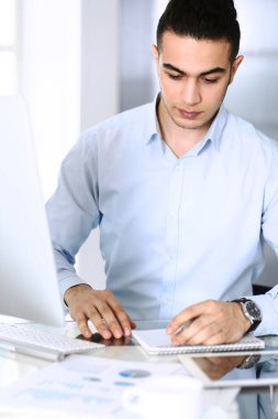 Modern ofiste bilgisayarla çalışan bir iş adamı. Arap erkek girişimcinin ya da iş yerindeki müdürün vesikalığı. İş konsepti