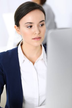 Ofiste bilgisayarla çalışan bir iş kadını, arka planda çalışan bir iş arkadaşı. Masada otururken avukatın ya da muhasebecinin vesikalığı.