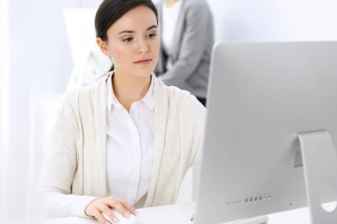 Ofiste bilgisayarla çalışan bir iş kadını, arka planda çalışan bir iş arkadaşı. Masada otururken avukatın ya da muhasebecinin vesikalığı.