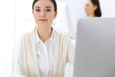 Ofiste bilgisayarla çalışan bir iş kadını, arka planda çalışan bir iş arkadaşı. Masada otururken avukatın ya da muhasebecinin vesikalığı.